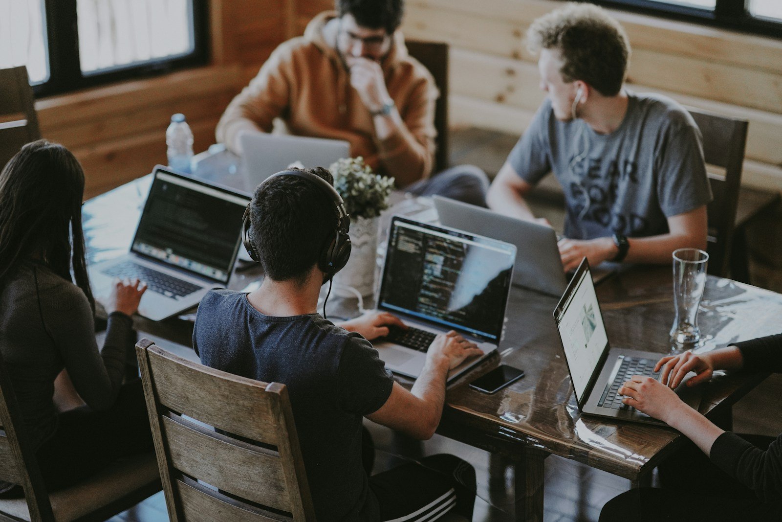 People with laptops at a shared table in a workspace.